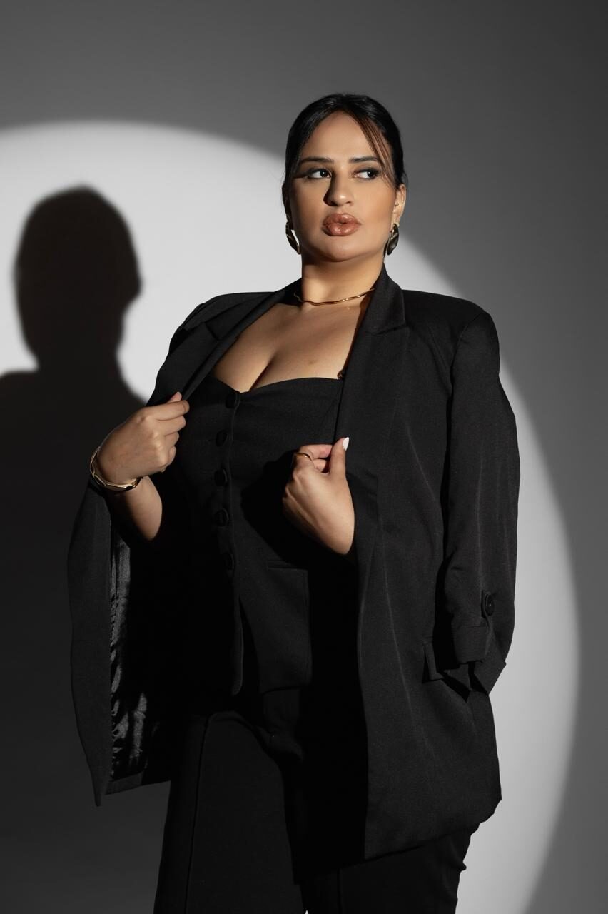 Profissional Vivaly em traje preto sob luz de estúdio